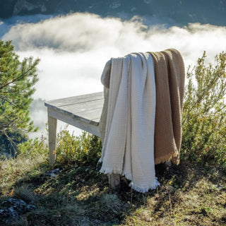 Cotton muslin throws draped casually over a bench.