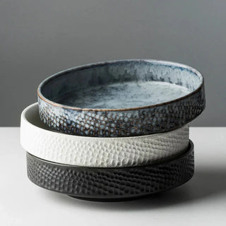 Stack of three embossed ceramic deep plates in blue, white, and black from the Suki collection by Arkaim Home.