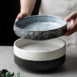 Stack of three embossed ceramic deep plates in blue, white, and black from the Suki collection by Arkaim Home.