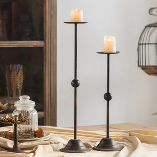 Two-size black iron candle holders with lit pillar candles.