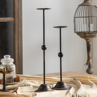 Vintage-style black metal candle holders in minimalist dining setting.