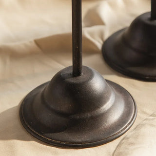 Minimalist black metal candle holder on neutral linen tablecloth.