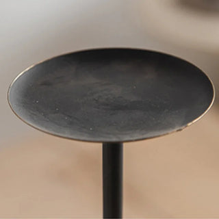 Minimalist black metal candle holder on neutral linen tablecloth.