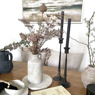 Sculptural speckled white ceramic vase styled with dried stems.