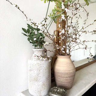 Rounded decorative ceramic vases with tapered necks styled with floral arrangements.