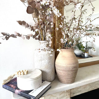 Rounded decorative ceramic vases with tapered necks styled with floral arrangements.