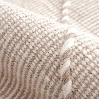 Handwoven taupe and white wool rug with geometric kilim pattern and braided fringe for modern, boho and nordic interiors.