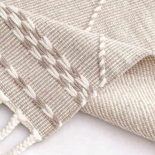 Handwoven taupe and white wool rug with geometric kilim pattern and braided fringe for modern, boho and nordic interiors.