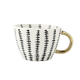 Handmade ceramic cup with black and white geometric design and a gold handle, minimalist and artistic in style.