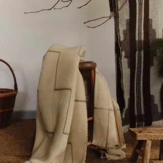 Heritage wool blankets draped over a wooden chair in a cosy room setting.