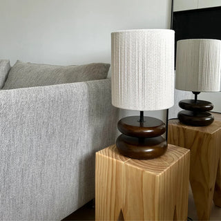 Yuni walnut table lamp with smooth wooden base and handwoven fabric shade, minimalist lighting for bedside, console, or living spaces.