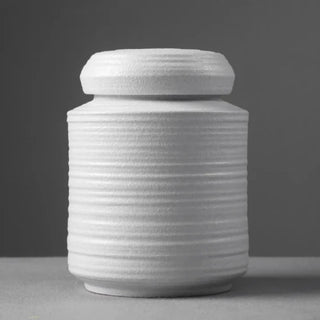 Elegant white ceramic storage jars in various shapes and sizes, featuring a ribbed textured finish and airtight lids. Perfect for storing tea, coffee, sugar, and spices while adding a modern, sophisticated touch to any kitchen countertop.