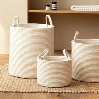 Small, medium and large white cotton rope laundry basket with handles for storing towels and styled in a bathroom.