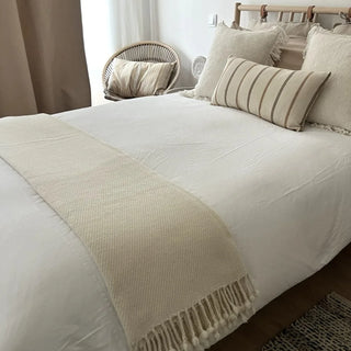 White merino wool throw draped over boho chic bed.