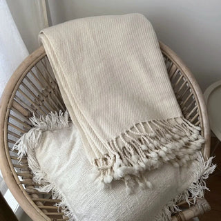 White merino wool throw draped over rattan chair.