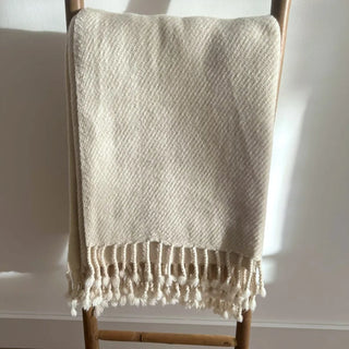 Lightweight natural merino blanket folded neatly on wooden ladder.