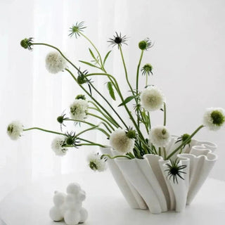 White fluted ceramic vase styled with small floral arrangement.