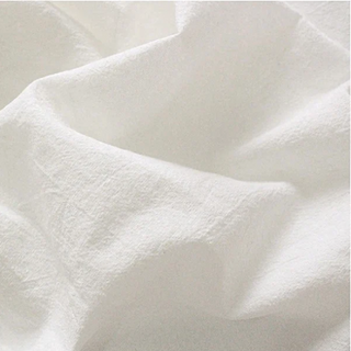 Handmade white cotton tablecloth with soft texture and elegant drape, styled for a modern, minimalist dining setting.