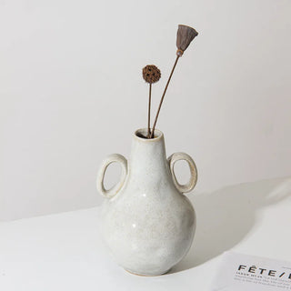 White nordic vase with double handles and glazed finish. Decorative accessory for shelves, coffee tables or sideboards in minimalist interiors.