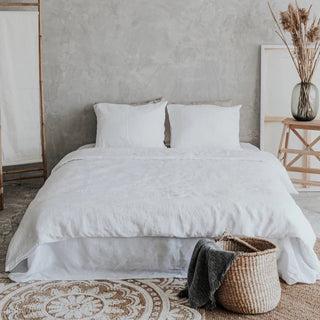 White linen bedding set with zip closure, styled on a bed with pillows and a cozy duvet, creating a calm, minimalist bedroom look.