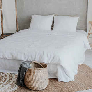 White linen bedding set with zip closure, styled on a bed with pillows and a cozy duvet, creating a calm, minimalist bedroom look.