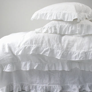 White ruffled linen pillows and duvet cover on a minimalist bed with a neutral background. Perfect linen bedding set for modern, boho or scandi bedrooms.