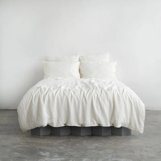 White linen pillows and duvet cover with coconut buttons, styled in a minimalist, scandi bedroom.
