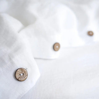Close-up of a white linen duvet cover with coconut buttons. Perfect for minimalist, scandi, boho or costal bedrooms.