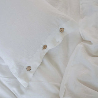 Close-up of a white linen pillowcase and duvet cover with coconut buttons. Perfect for minimalist, scandi, boho or costal bedrooms.