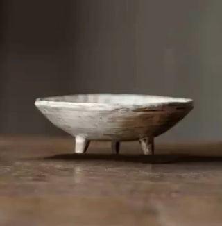 White handmade ceramic raised serving dish with an uneven, textured surface and hand-rubbed glaze. This wabi-sabi inspired decorative fruit bowl adds a natural, organic touch to any home. Perfect as a unique display piece or functional home accessory. Shop artisanal pottery at our natural homeware store.