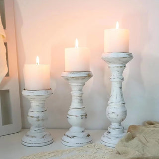 Three whitewashed wooden candle holders, arranged on a tabletop.