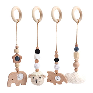 Handmade wood and crochet baby hanging toy pendant in soft neutral tones, suspended on a baby gym for sensory development.