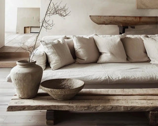 Minimalist zen living room interior featuring linen sofa and cushions, rustic wooden coffee table and large ceramic vase and bowl.