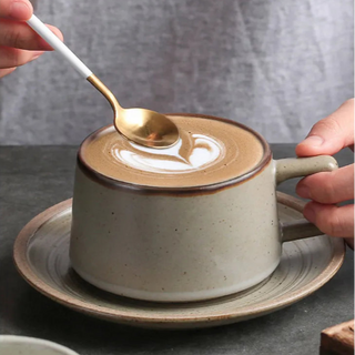 Biba ceramic coffee cup and saucer in speckled grey glaze with a latte and spoon