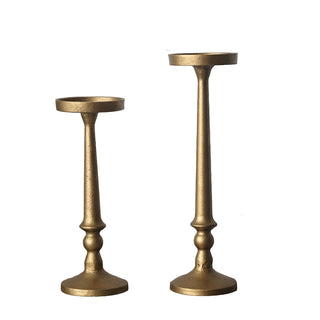 Two gold iron pillar candle holders, tall and short, on white