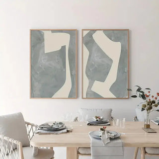 Set of two abstract geometric canvas prints featuring soft cream shapes on a textured grey background; minimalist wall art for serene, modern interiors.