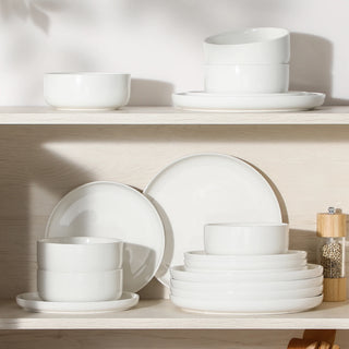 White ceramic plates and bowls stacked on a wooden shelf
